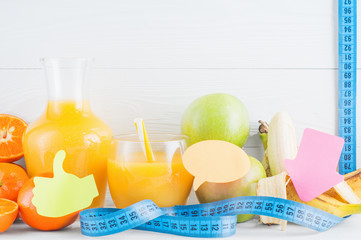 A glass of fresh orange juice and fruits, orange, tangerine, apple, banana and measuring tape on...