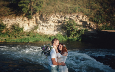 the bride and groom on the background of a mountain stream