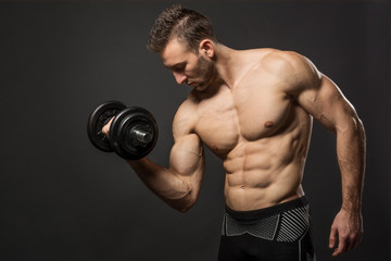Fototapeta na wymiar Handsome muscular man working out with dumbbells