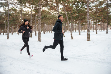 Man and woman running in the snow in the woods