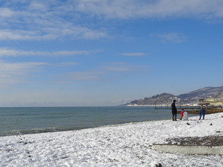 Family making snowman on snowy beach, coast Sochi, Russia