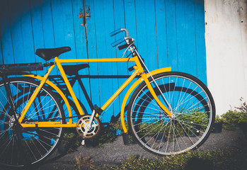 Yellow old vintage bicycle leaning against on vintage wood wall background in the sun. Bicycle vintage for decorate concept.