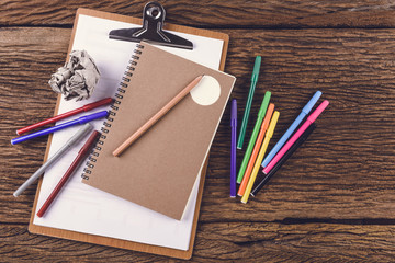 pencil with notebook and Magic Colors on Wooden background