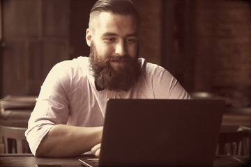 Portrait of a young bearded businessman working with laptop (Suc