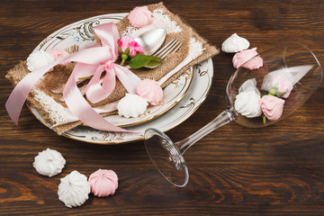 Light pink roses and tableware on the wooden table