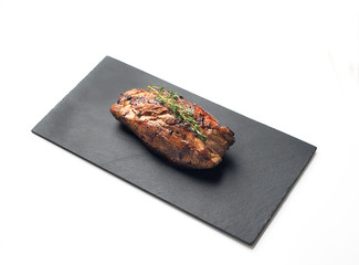 grilled beef steak on a black slate board. On a white background