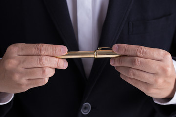 A man in black casual suit holding a gold fountain pen for sign the contract in formal way