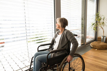 Disabled senior woman in wheelchair at home in living room.