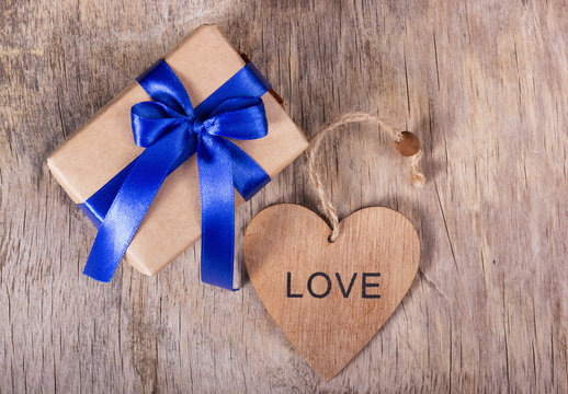 Gift on Valentine's Day. Gift box with a blue bow and a wooden heart. Copy space. Valentine's day.
