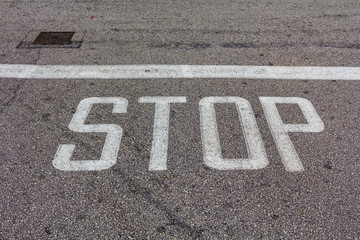 Fototapeta na wymiar Word Stop written on an asphalt road, Stop Sign