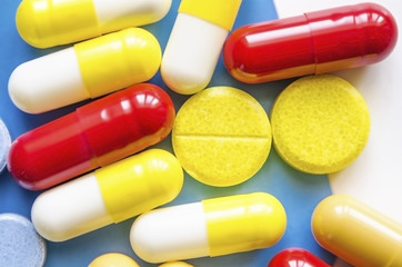 Colorful medicine pills, drugs and capsules on a white and blue background. Selective focus. Close-up macro shot.