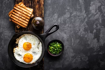 Wall murals Fried eggs fried eggs on dark background with space for text