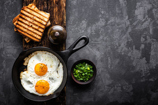 fried eggs on dark background with space for text