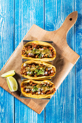Mexican tacos campechanos top view on a blue wooden table. © funkyfrogstock