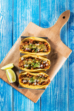Mexican tacos campechanos top view on a blue wooden table.