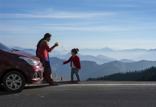 Mother and daughter enjoying the road trip and winter vacation. Car travel vacation concept photo against Himalayan mountain in the background.