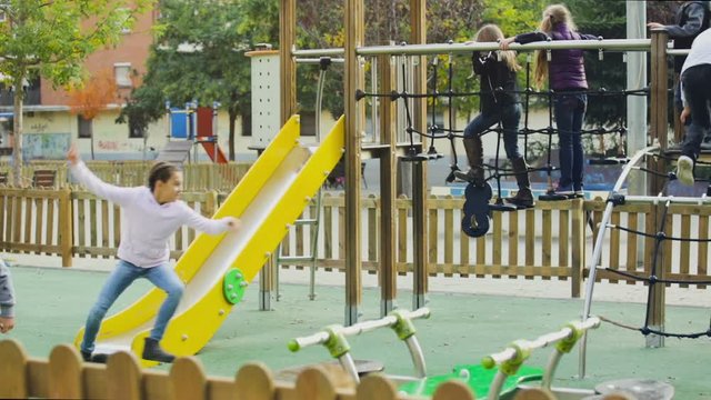 cheerful boy and girls in elementary school age having fun on slide 