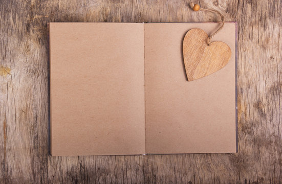 Open book with blank pages and a bookmark made of wood. Wooden heart. Personal diary. Valentine's Day. Copy space