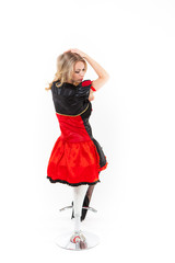 Young blond caucasian women in red dress is sitting on bar chair - Red Queen cosplay, white backgrond