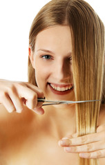 Attractive young woman is cutting her long natural hair.