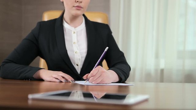 The girl writting on the paper in the office