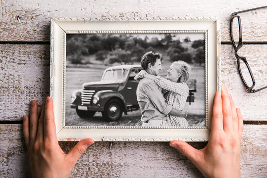 Hands holding black-and-white photo of seniors in picture frame