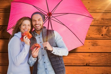 Composite image of happy young couple holding umbrella