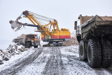 excavator loading granite or ore into dump truck at opencast