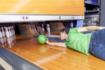 young man sliding down a bowling alley