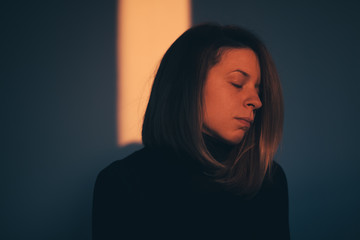 A woman sitting alone and depressed in window light