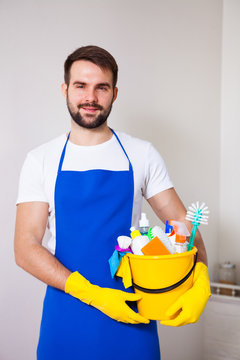 Man holding plastic bucket with bottles and brushes, gloves and