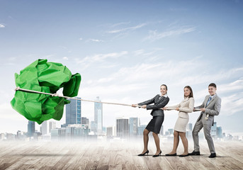 Young business people outdoors and huge paper ball as symbol of creativity