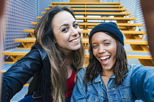 two mixed race female friends sitting and using a smartphone