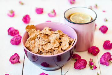 Romantic breakfast with cereal and tea with lemon and dry roses