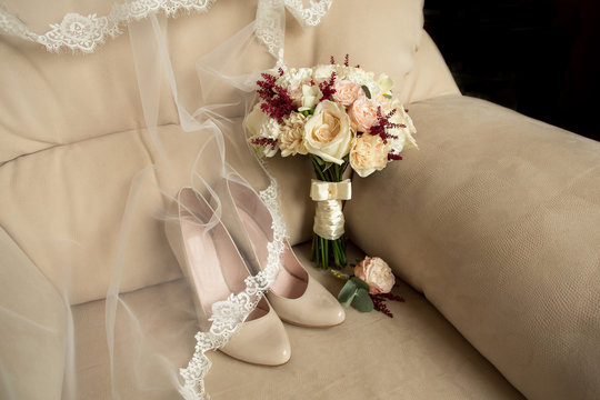 Bridal shoes and wedding bouquet on armchair