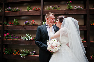 Beautiful wedding couple stay background wall with flowers on po