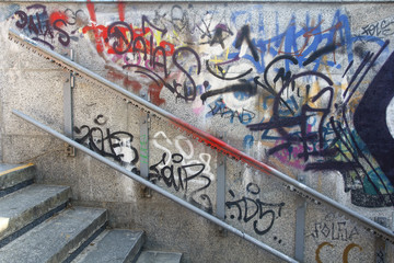 Old metal handrail on a wall with graffiti and the stairs