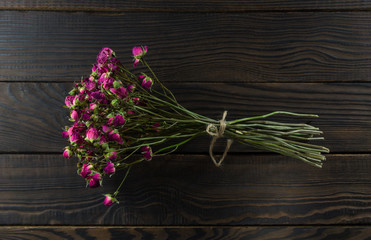 Bouquet of dry flowers with ribbon on dark wooden surface