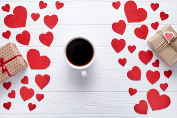 A cup of coffee on the white wooden table with hearts and gifts boxs. Romantic background to Valentine's Day, Dating, couples in love. Flat lay.
