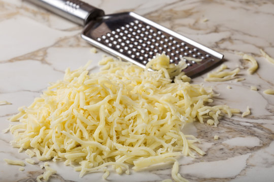Grated mix cheese and one stainless steal grater in background