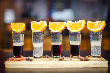 Little alcoholic cocktail at the bar. Multi-colored cocktail. Colorful cocktail at the bar. Orange on the cocktail. Cocktail on the side.