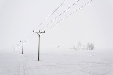 Electricity pylons from distribution power station in foggy winter freeze