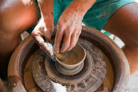Hands of man spinning clay on pottery wheel 