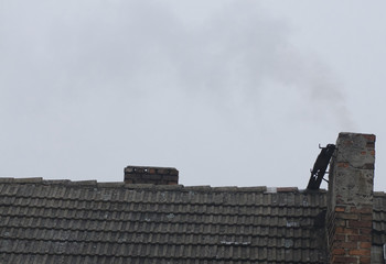 Smoke from chimneys over a town / city roofs 