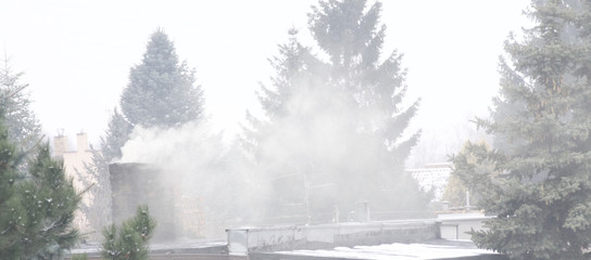 Smoke from chimneys over a town / city roofs 