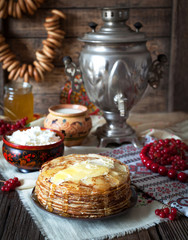 Traditional russian pancakes with cottage cheese, milk, butter and sour cream on napkins with embroidery. Traditional dishes on the holiday Carnival Shrovetide