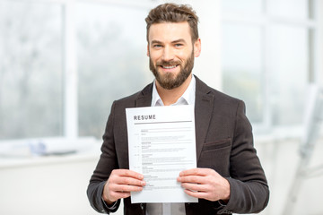 Elegant man in the suit holding resume for job hiring in the bright interior