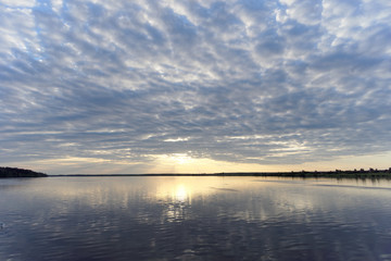 View of the golden sunset on the river with clouds and the Sun reflected in it, Volga, Russia