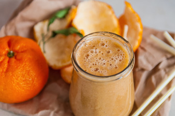 Close up Fresh homemade tangerine smoothie in glass bottle on white wooden background, soft selective focus