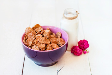 Flakes with milk for a romantic breakfast on a wooden light background with dry flowers.